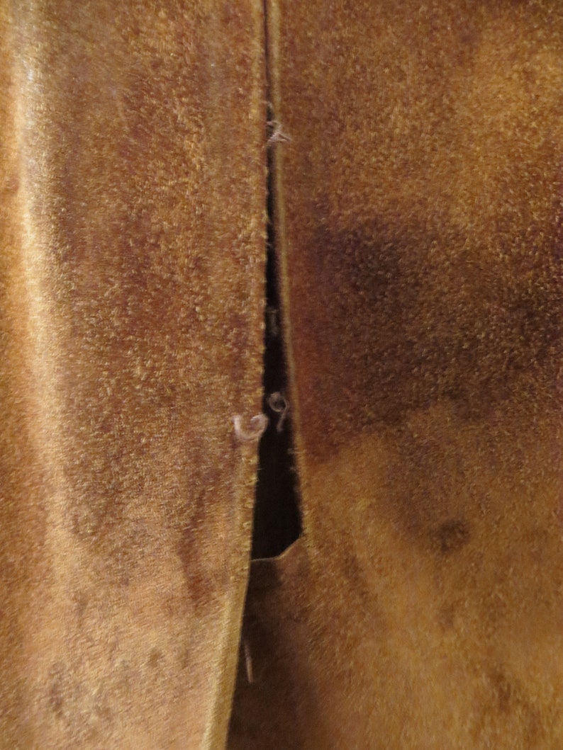 May include: Close-up of a brown suede jacket with a seam down the back.