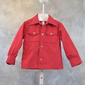May include: A bright red button-down shirt with two chest pockets and a collar. The long-sleeved shirt has buttoned cuffs and is displayed on a white hanger. The shirt is made of a solid color fabric.