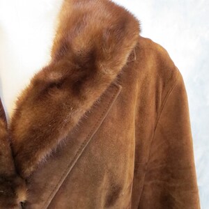 May include: A brown suede jacket with a brown fur collar. The jacket has a long sleeve and a button closure.