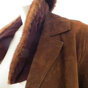 May include: A brown suede jacket with a fur collar. The collar is made of a soft, brown fur.