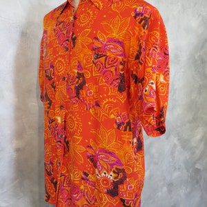 May include: A short-sleeved button-down shirt with a vibrant orange, pink, and yellow patterned design. The pattern features geometric shapes and floral motifs.