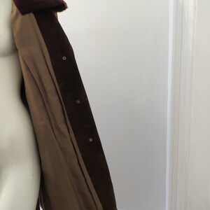May include: A brown suede jacket with a fur collar. The jacket is open and the lining is visible. The lining is a light brown colour.
