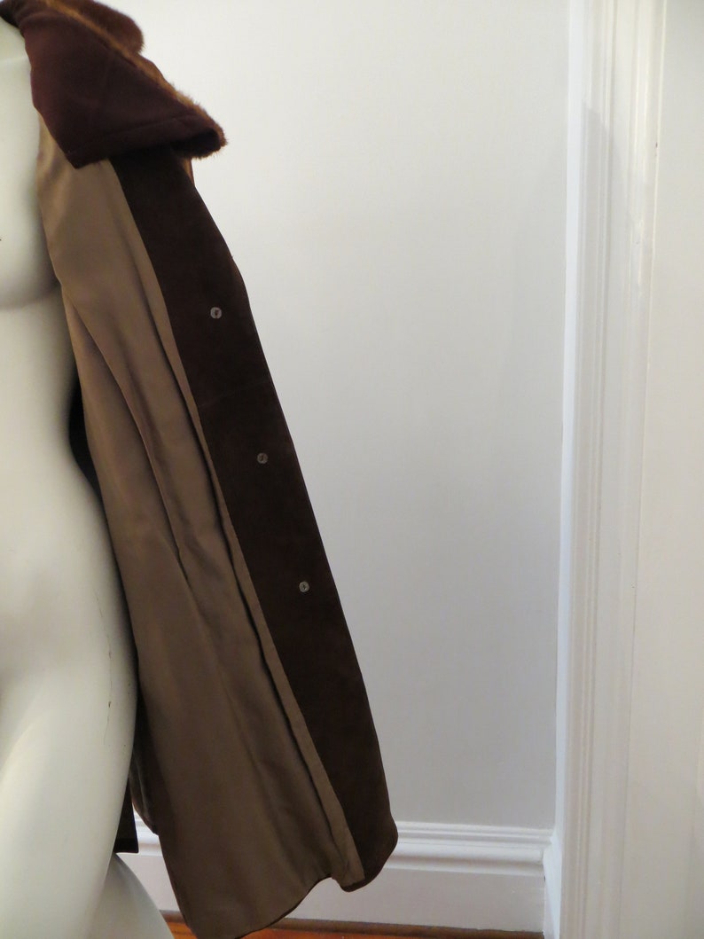 May include: A brown suede jacket with a fur collar. The jacket is open and the lining is visible. The lining is a light brown colour.