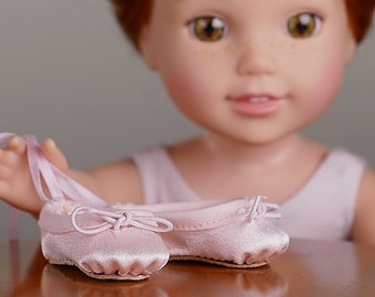 May include: A pair of pink satin ballet shoes with satin ribbons. The shoes are on a wooden table with a doll in the background.