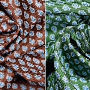 May include: Two fabric swatches with paisley patterns. The left swatch is brown with blue paisley designs. The right swatch is forest green with blue paisley designs. Both swatches are labelled with the text "100% Silk Twill".