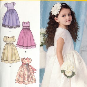 May include: Simplicity sewing pattern 1507 for girls' dresses. The pattern features illustrations of four different dress designs, including a white dress worn by a young girl. The pattern includes sizes 4-8.