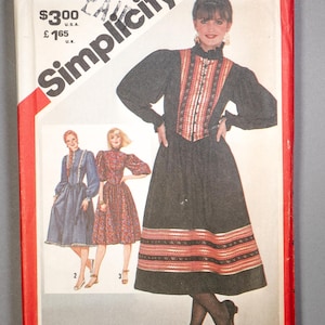 May include: A vintage Simplicity sewing pattern envelope showing a woman in a black dress with red and white trim. The envelope has a red border and the Simplicity logo. The size is listed as 8.