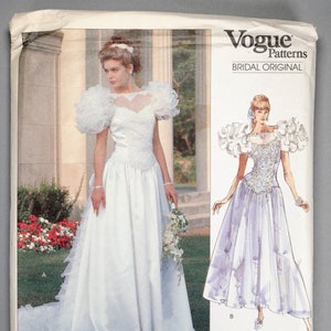 May include: Vogue Patterns bridal original sewing pattern, featuring two illustrations of wedding dresses. The dress on the left is white with a large, ruffled neckline and a long train. The dress on the right is lavender with a ruffled neckline and a shorter skirt. The pattern number is 2398.