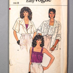 May include: A sewing pattern envelope with the text "Very Easy Vogue" and the number "8662". The envelope shows three illustrations of women wearing different outfits. The first woman is wearing a white blouse with a purple tank top underneath, the second woman is wearing a white blouse with a white tank top underneath, and the third woman is wearing a purple tank top with a white skirt. The pattern is for size 8.
