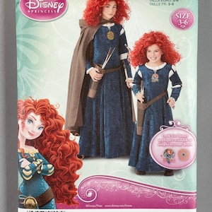 May include: A Simplicity sewing pattern envelope for a Disney Princess Brave costume, featuring a dark blue velvet-textured dress with a brown cape, quiver, and arrows. The package displays the number 1557 HH, size 3-6, and illustrations of the character Merida.