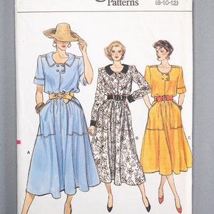 May include: Vogue Patterns 9521. A vintage sewing pattern featuring illustrations of three dresses. The dresses are in blue, white floral, and yellow, each with a belt. The pattern size is (8-10-12).