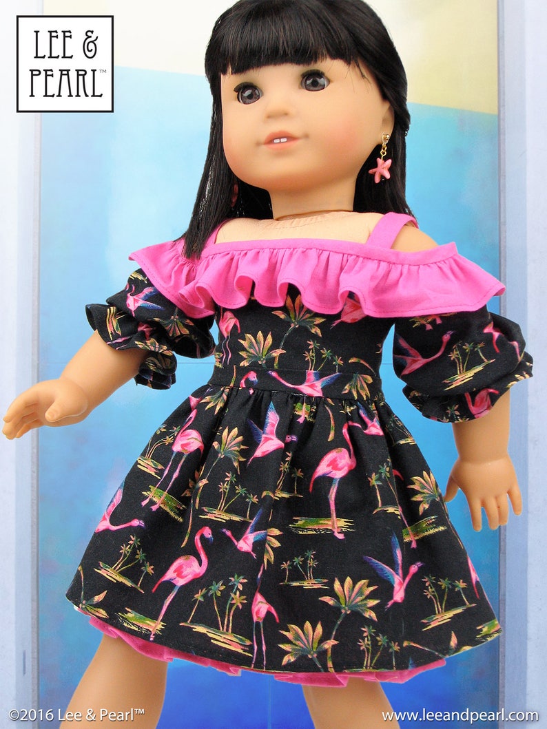 May include: A pink and black doll dress with a flamingo print and pink ruffle trim. The dress has a cold shoulder style and is perfect for a doll.