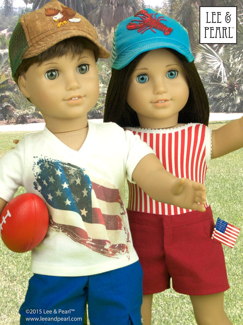May include: Two dolls wearing summer outfits. The doll on the left is wearing a white t-shirt with an American flag design, blue shorts, and a brown and green baseball cap with an eagle design. The doll on the right is wearing a red and white striped tank top, red shorts with a small American flag patch, and a blue baseball cap with a red lobster design. The text "LEE & PEARL" is visible in the top right corner of the image.