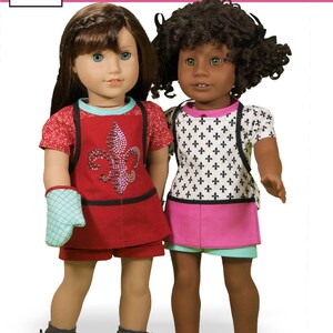 May include: Two 18-inch dolls wearing different outfits. The doll on the left is wearing a red and black outfit with a blue and white oven mitt. The doll on the right is wearing a white and black patterned shirt with a pink and blue skirt.