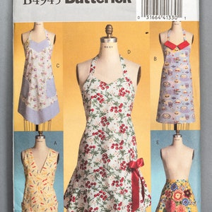 May include: A Butterick sewing pattern featuring various apron designs. The aprons showcase diverse patterns, including floral, cherry, and dessert motifs. The pattern includes a size range from small to large, indicated as (Sml-Med-Lrg).