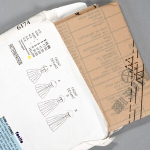 May include: A white envelope with a sewing pattern inside. The pattern is for a dress and includes instructions for two different styles. The envelope has a price tag with prices in US dollars, Canadian dollars, Australian dollars, New Zealand dollars, South African Rand, and UK pounds.