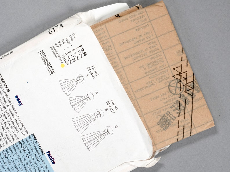 May include: A white envelope with a sewing pattern inside. The pattern is for a dress and includes instructions for two different styles. The envelope has a price tag with prices in US dollars, Canadian dollars, Australian dollars, New Zealand dollars, South African Rand, and UK pounds.