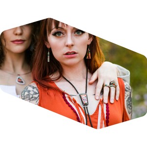 Puede incluir: Dos mujeres con joyas, una con un bolo tie colorido y la otra con un collar con colgante. Ambas mujeres llevan pendientes.