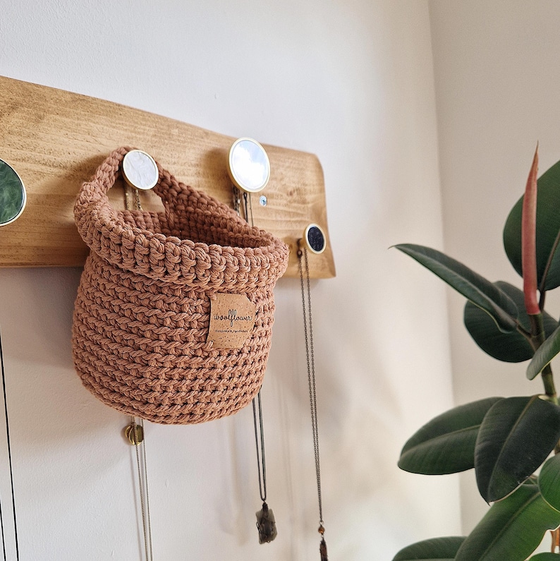 A light salmon brown hanging crochet baskets with a vegan friendly cork "woolflower" logo. Great for bedrooms, bathrooms and nursery for storing toiletries, make-up, vitamins, pegs, etc. Natural home organisation on Etsy by Woolflowerdesigns!