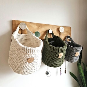 Natural, olive green and grey coloured crochet hanging storage baskets in small, medium and large. Great for nursery, bathroom, bedroom and hallway organisation and storage. Made by WoolflowerDesigns on Etsy