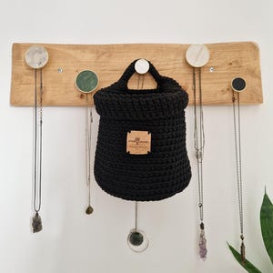 A black hanging crochet baskets with a vegan friendly cork "woolflower" logo. Great for bedrooms, bathrooms and nursery for storing toiletries, make-up, vitamins, pegs, etc. Natural home organisation on Etsy by Woolflowerdesigns!