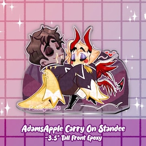 May include: A 3.5-inch tall epoxy standee featuring two cartoon characters embracing. One character has brown hair and a black outfit with gold accents. The other has blonde hair, red horns, and a black outfit with red wings. The standee has the text "AdamsApple Carry On Standee".