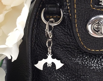 May include: Black leather handbag with a yellow stitch detail and a silver bat charm attached to the zipper pull.