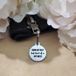 May include: A white metal keychain with the text "Doing my best but kind of a hot mess" in black lettering.