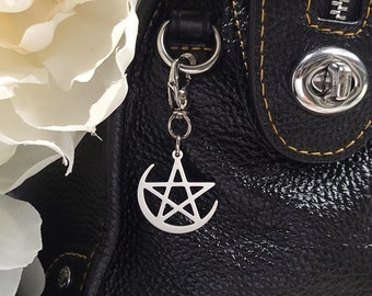 May include: A black leather handbag with a silver pentagram charm attached to the zipper pull. The bag has a yellow stitch detail around the edges.