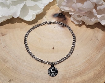 May include: A silver chain necklace with a black circular pendant featuring a white crescent moon and a symbol.