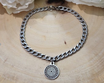 May include: A silver chain necklace with a round pendant featuring a geometric design. The pendant has a detailed pattern of interlocking circles and lines.