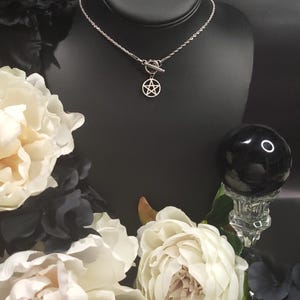 Op de afbeelding: Een zilveren ketting met een zilveren pentagram hanger en een schuifgesp. De ketting wordt getoond op een zwarte mannequinbuste.