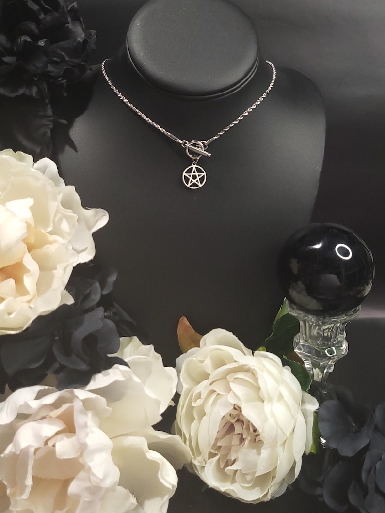 Op de afbeelding: Een zilveren ketting met een zilveren pentagram hanger en een schuifgesp. De ketting wordt getoond op een zwarte mannequinbuste.