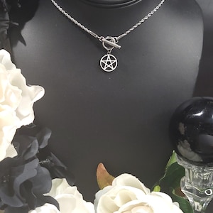 Op de afbeelding: Een zilveren ketting met een zilveren toggle sluiting en een zilveren pentagram hanger.