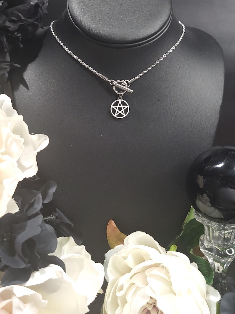 Op de afbeelding: Een zilveren ketting met een zilveren toggle sluiting en een zilveren pentagram hanger.