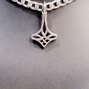 May include: A silver chain necklace with a silver pendant shaped like a four-pointed star with a knot design.