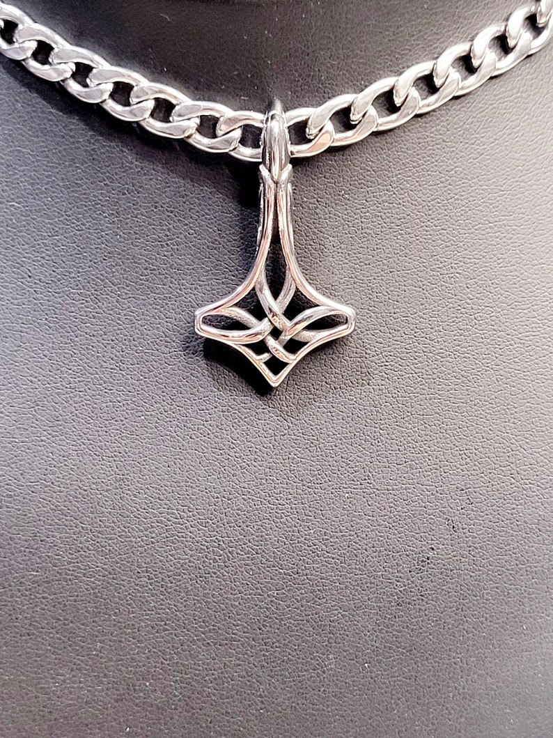 May include: A silver chain necklace with a silver pendant shaped like a four-pointed star with a knot design.
