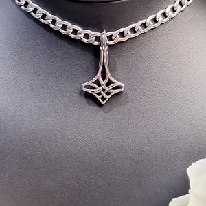 May include: A silver chain necklace with a silver pendant featuring a geometric design. The pendant is shaped like a diamond with intricate details.