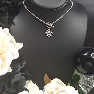 Op de afbeelding: Een zilveren ketting met een zilveren toggle sluiting en een zilveren pentagram hanger.