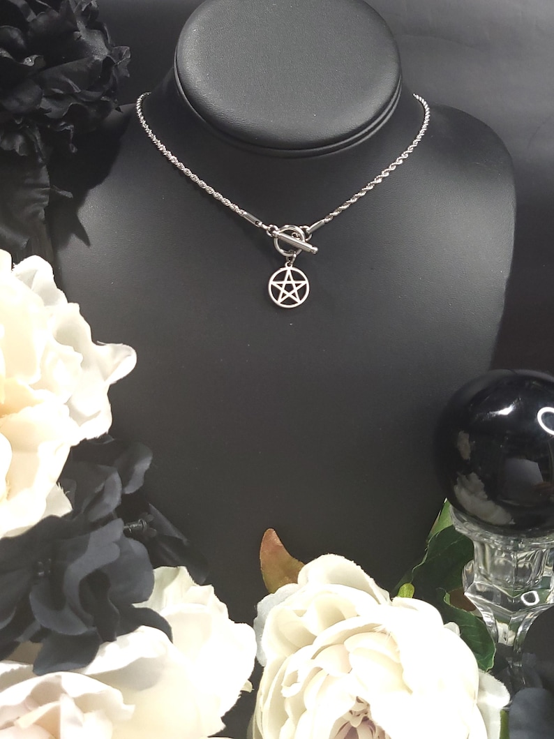 Op de afbeelding: Een zilveren ketting met een zilveren toggle sluiting en een zilveren pentagram hanger.