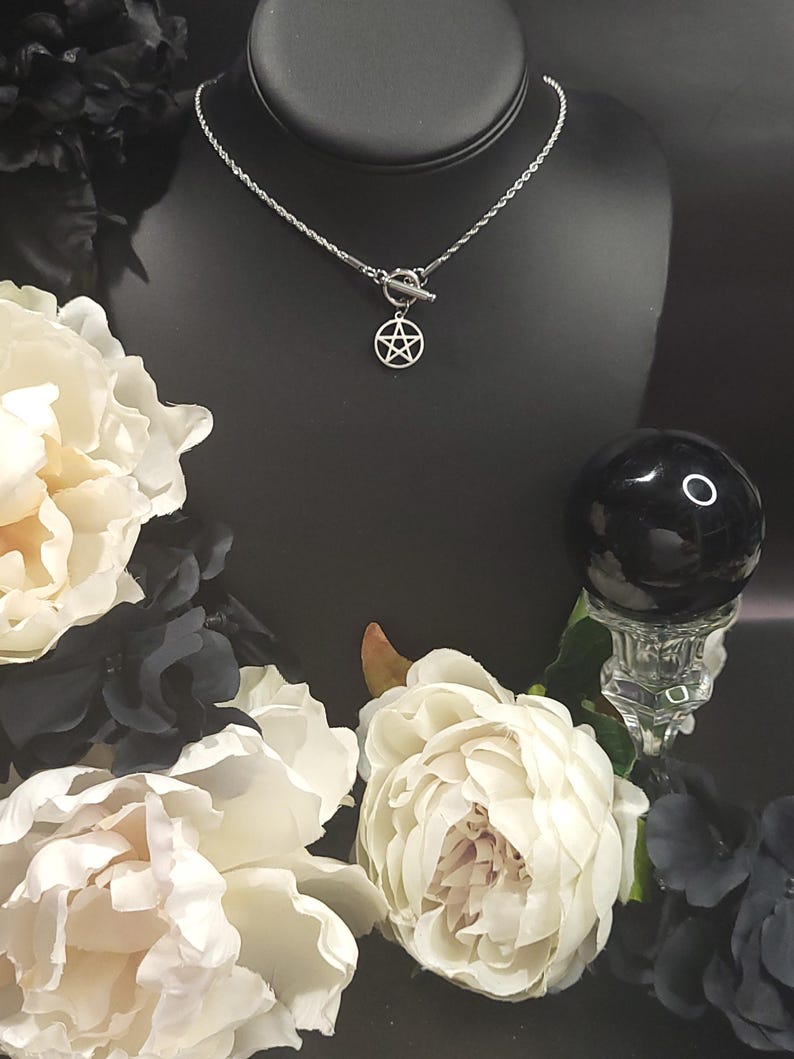 Op de afbeelding: Een zilveren ketting met een zilveren toggle-sluiting en een zilveren pentagram-hanger. De ketting wordt getoond op een zwarte mannequin-buste.