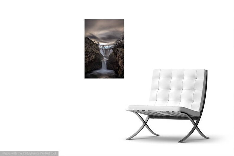 May include: A dramatic black and white photograph of a waterfall cascading down a rocky cliff face. The water is blurred, creating a sense of motion. The sky above is cloudy and dark.