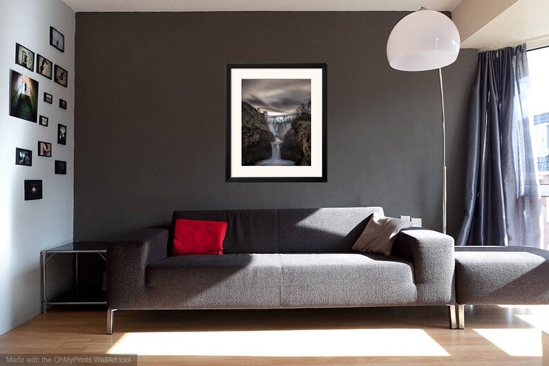 May include: A framed photograph of a waterfall cascading down a rocky cliff. The photo is in a black frame and is hanging on a gray wall in a living room setting.