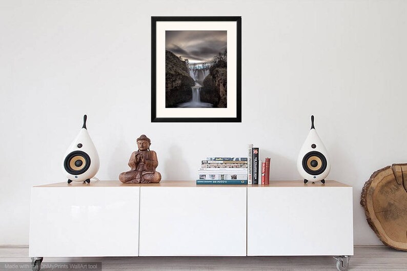 May include: A framed photograph of a waterfall cascading down a rocky cliff. The sky is overcast and the scene is dramatic.
