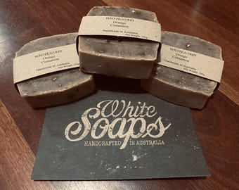 May include: Three bars of handmade soap with brown paper labels. The labels read "WHITESOAPS Orange Cinnamon Handmade in Australia". The soaps are on a dark grey slate with "White Soaps HANDCRAFTED IN AUSTRALIA" printed on it.