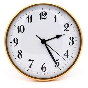 May include: A gold-framed clock with black hands and black numbers on a white face. The clock face has a subtle sheen.