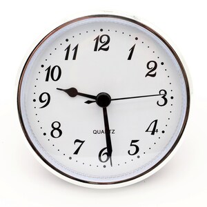 May include: A white analog clock with black hands and black numbers on a silver face. The clock face has a silver rim and a silver bezel. The clock is set to 10:10 and reads "QUARTZ".