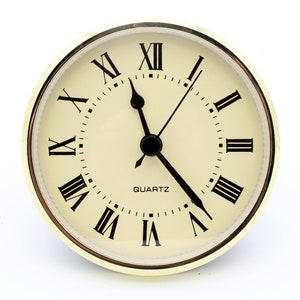 May include: A gold-toned clock with Roman numeral markings and a white face. The clock reads "QUARTZ" and has black hands.