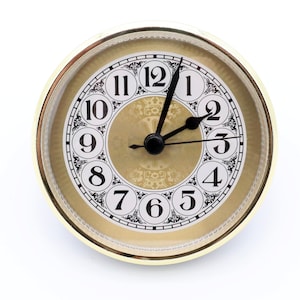 May include: A gold-toned clock face with black Roman numeral hour markers and black hands. The clock face has a decorative design with a gold background and black accents.