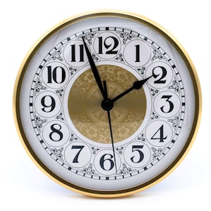 May include: A gold-framed clock with black hands and Roman numeral markings on a white face. The clock face has a decorative gold center with a floral pattern.